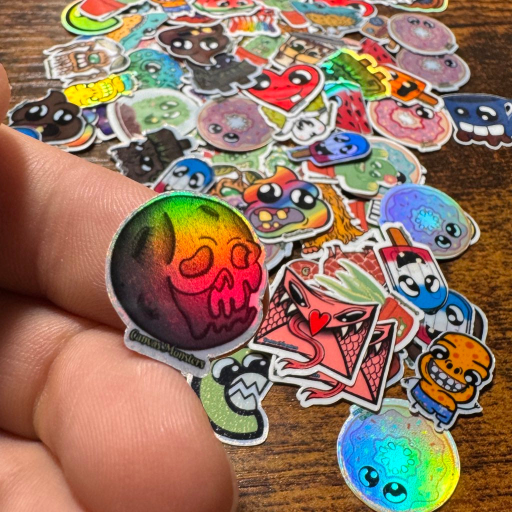 Collection of colorful cartoon-style stickers on a wooden surface with a single finger holding a moon themed character sticker