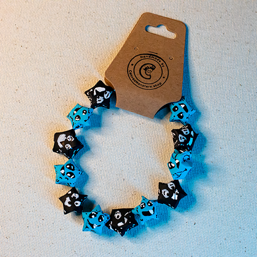 Bracelet with alternating blue and black paper origami star-shaped charms on a beige background