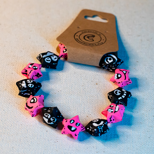 Bracelet with alternating black and pink paper origami star-shaped charms on a beige background