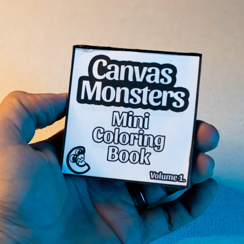 Hand holding a mini coloring book titled 'Canvas Monsters Mini Coloring Book Volume 1' against a neutral background.