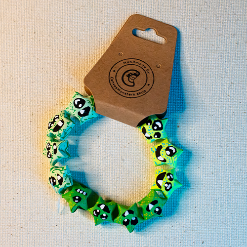 Bracelet with green paper origami star-shaped charms on a beige background