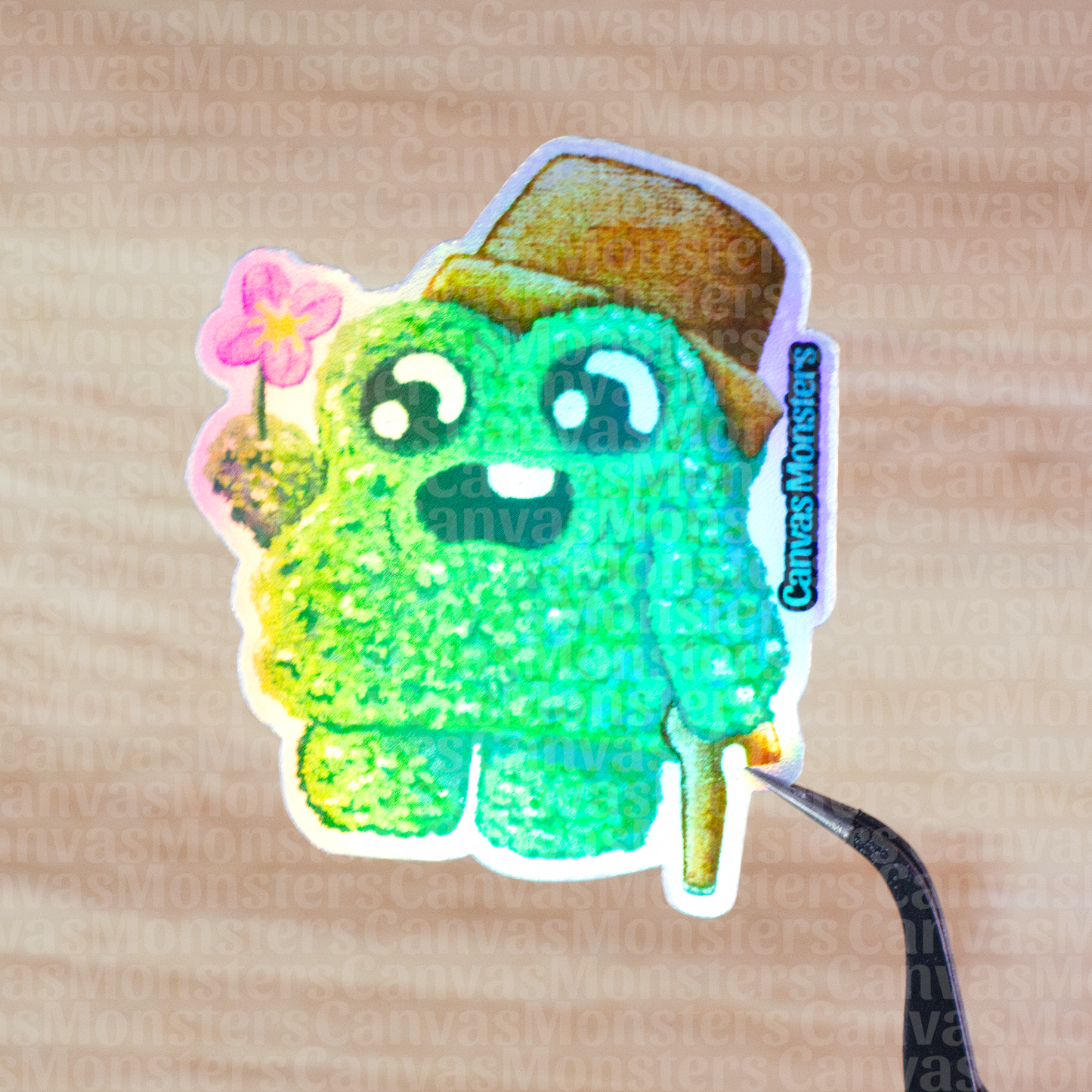 Holofoil sticker of a green shrub creature wearing a brown pot as a hat and holding a flower on a wooden surface