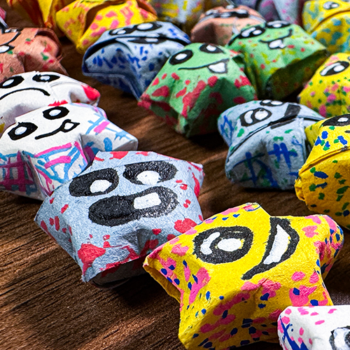 Close up image of origami paper stars with painted faces on them.