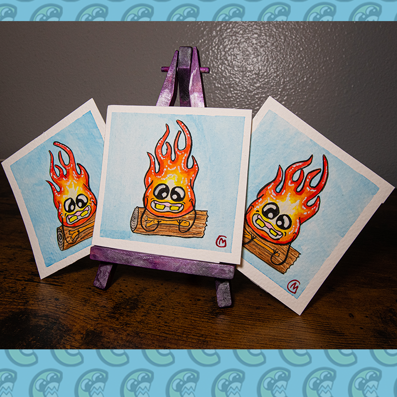 Three small, original watercolor paintings featuring a cartoon-style fire monster with a smiling face, painted on watercolor paper, with a white border displayed on a purple easel.