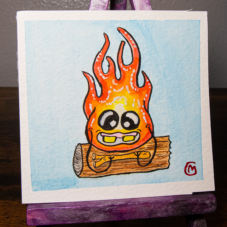A small, original watercolor painting featuring a cartoon-style fire monster with a smiling face, painted on watercolor paper, with a white border and a purple easel.