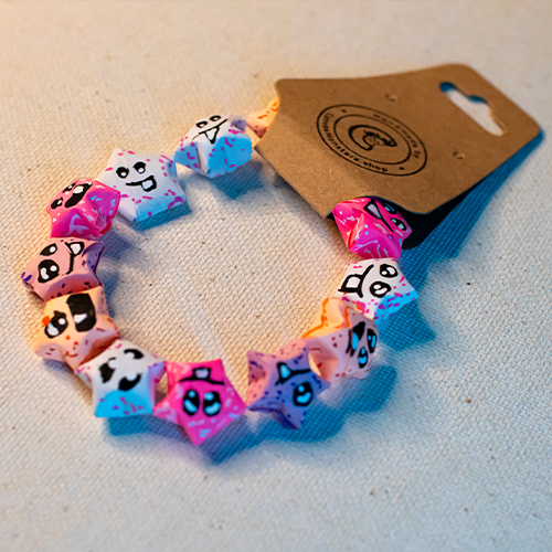 Bracelet with pink and white paper origami star-shaped charms on a beige background