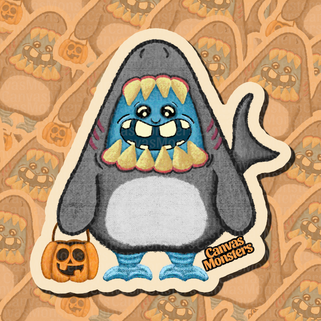 A die-cut sticker featuring a cartoon shark monster with blue skin, large yellow teeth, and a small orange pumpkin bucket, shown on a patterned tan background. The sticker has a visible 'Canvas Monsters' brand mark near the bottom right.