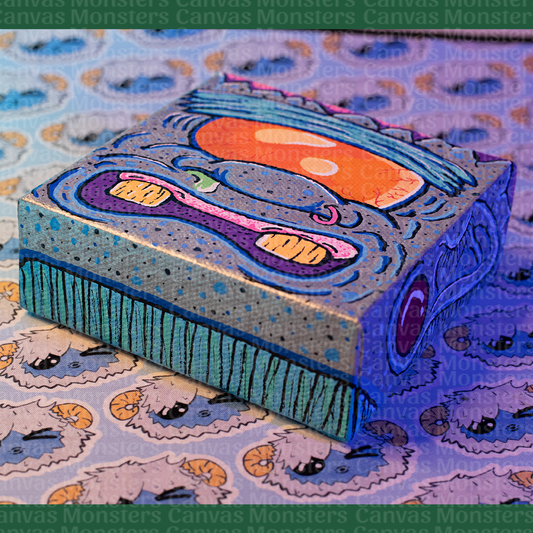 Colorful abstract Monster painting on a canvas block. Featuring a giant orange eye, blue skin, and silver highlights.