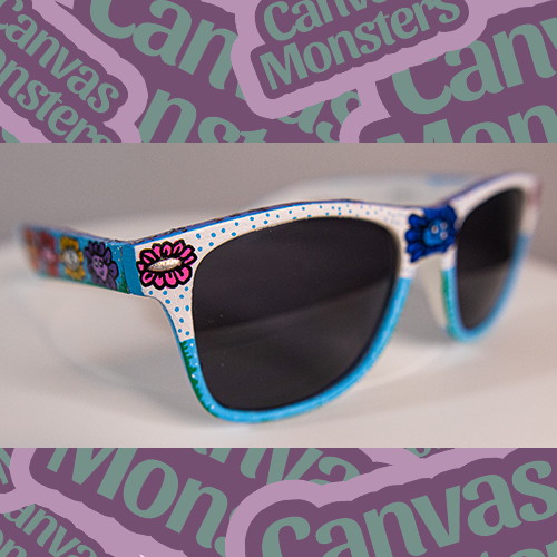 A pair of painted sunglasses with colorful character patterns on the frame, displayed on a white background with 'Canvas Monsters' text.