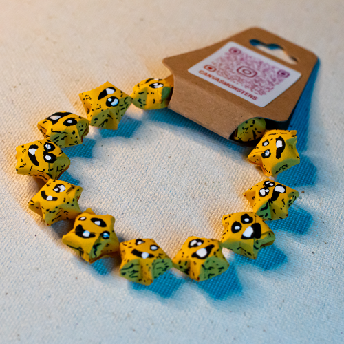 Bracelet with yellow paper origami star-shaped charms on a beige background