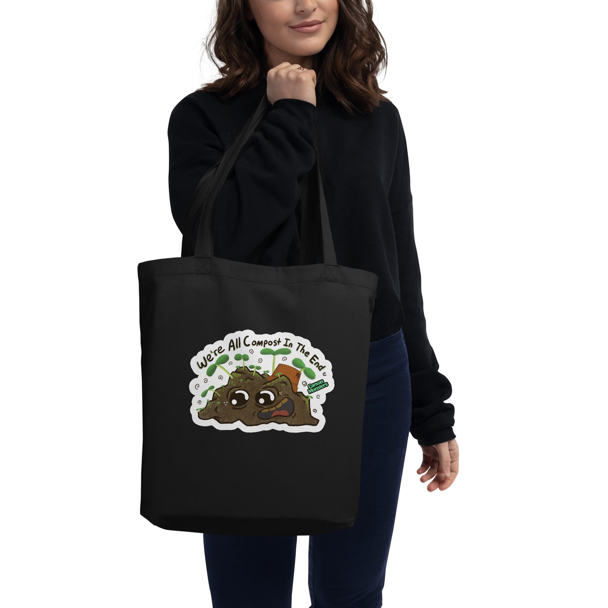 Person holding a black tote bag with a compost-themed design on a white background