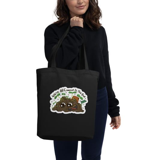 Person holding a black tote bag with a compost-themed design on a white background