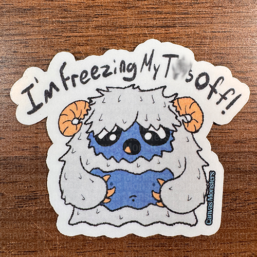 A sticker of a cartoon yeti character with text 'I'm freezing my tits off!' The background features a pattern of the same yeti character.