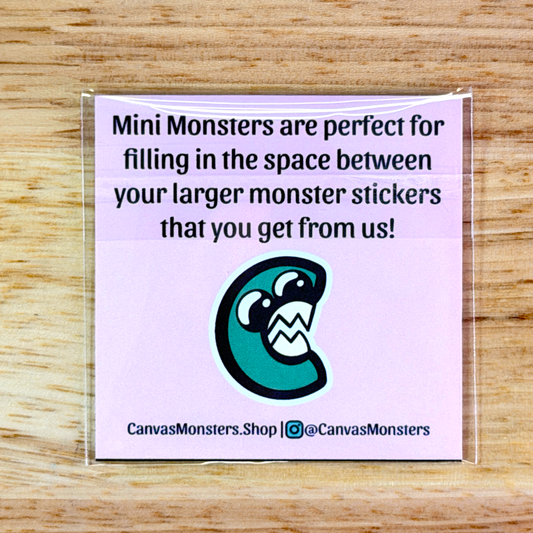 The back of the Mini Monsters packaging, with text that reads 'Mini Monsters are perfect for filling in the space between your larger monster stickers that you get from us!' with a monster C logo and 'CanvasMonsters.Shop' written at the bottom, sitting on a wooden background.