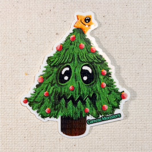 Sticker of a cartoon Christmas tree with a star on top, eyes, and mouth, branded 'Canvas Monsters', on a textured beige background.