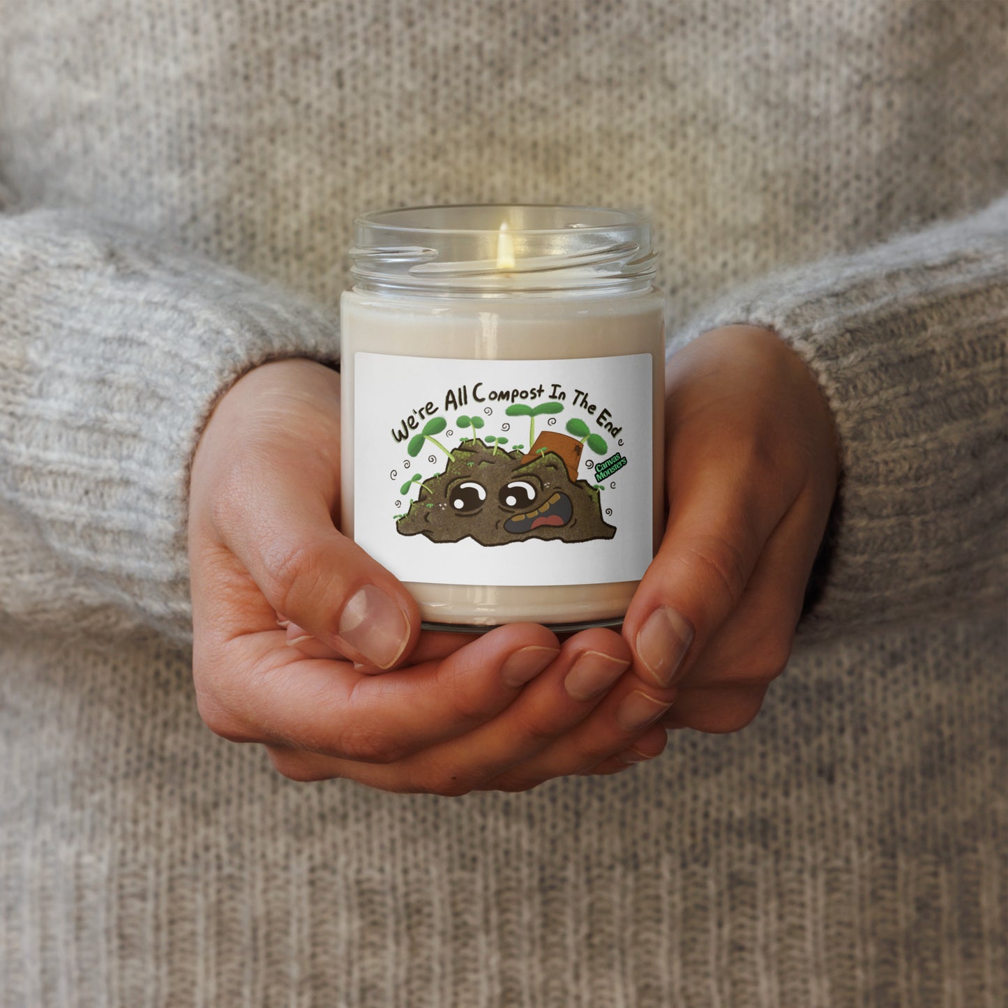 Candle in a glass jar held by hands with a label on a textured background