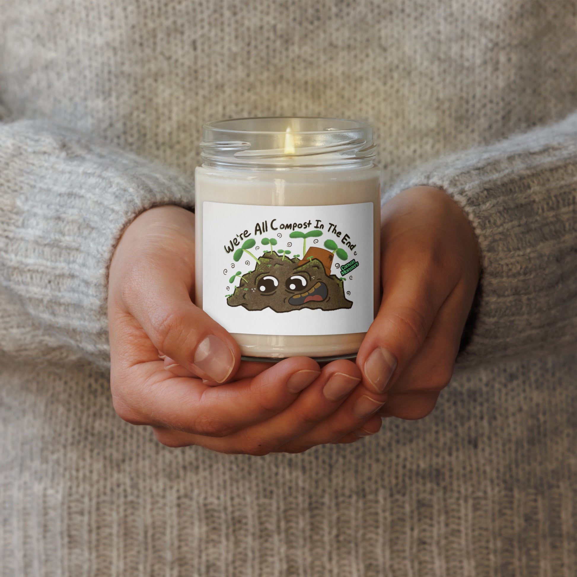 Candle in a glass jar held by hands with a label on a textured background