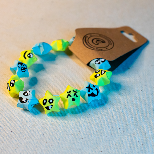 Bracelet with alternating blue and yellow paper origami star-shaped charms on a beige background