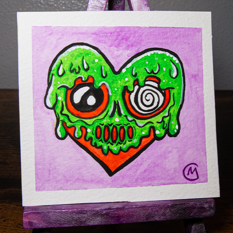 A watercolor painting of a heart-shaped monster with green slime and a purple background, displayed on a mini easel.