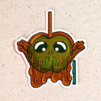 Sticker of a candy apple shaped creature sticker with green face and brown body on a beige background