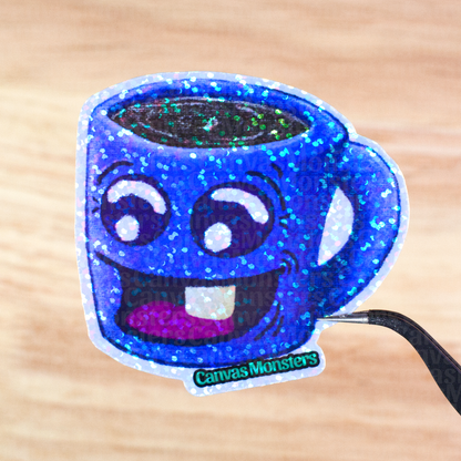 Glittery sticker of a blue mug with a happy face held above a wooden surface, branded 'Canvas Monsters'.