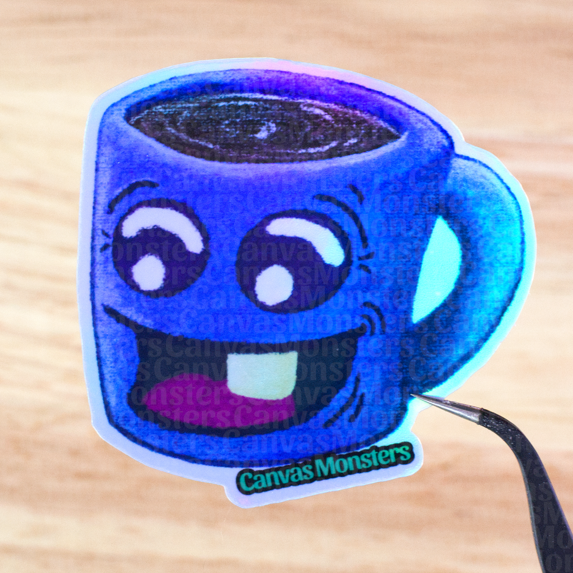 Holofoil sticker of a blue mug with a happy face held above a wooden surface, branded 'Canvas Monsters'.