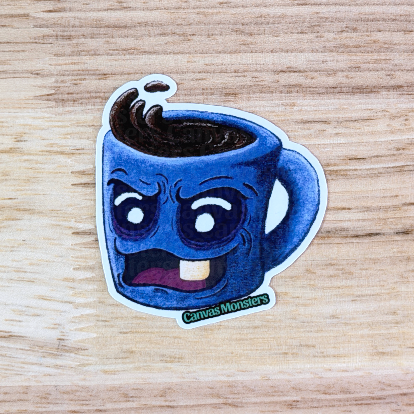 Sticker of a blue mug with a grumpy face sitting on a wooden surface, branded 'Canvas Monsters'.