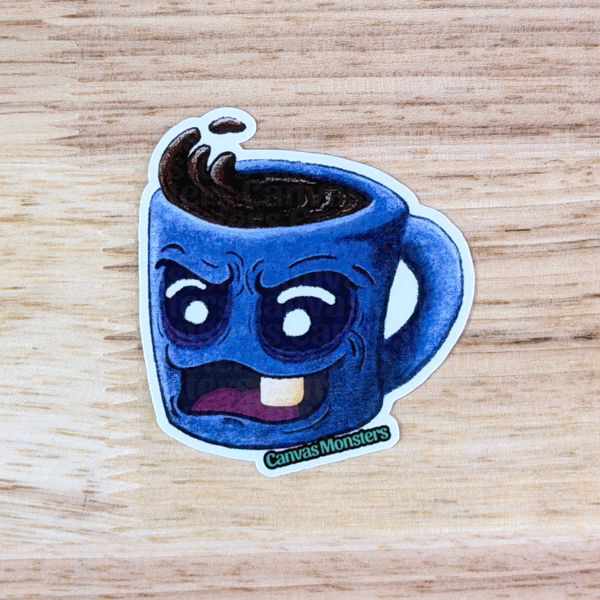 Sticker of a blue mug with a grumpy face sitting on a wooden surface, branded 'Canvas Monsters'.