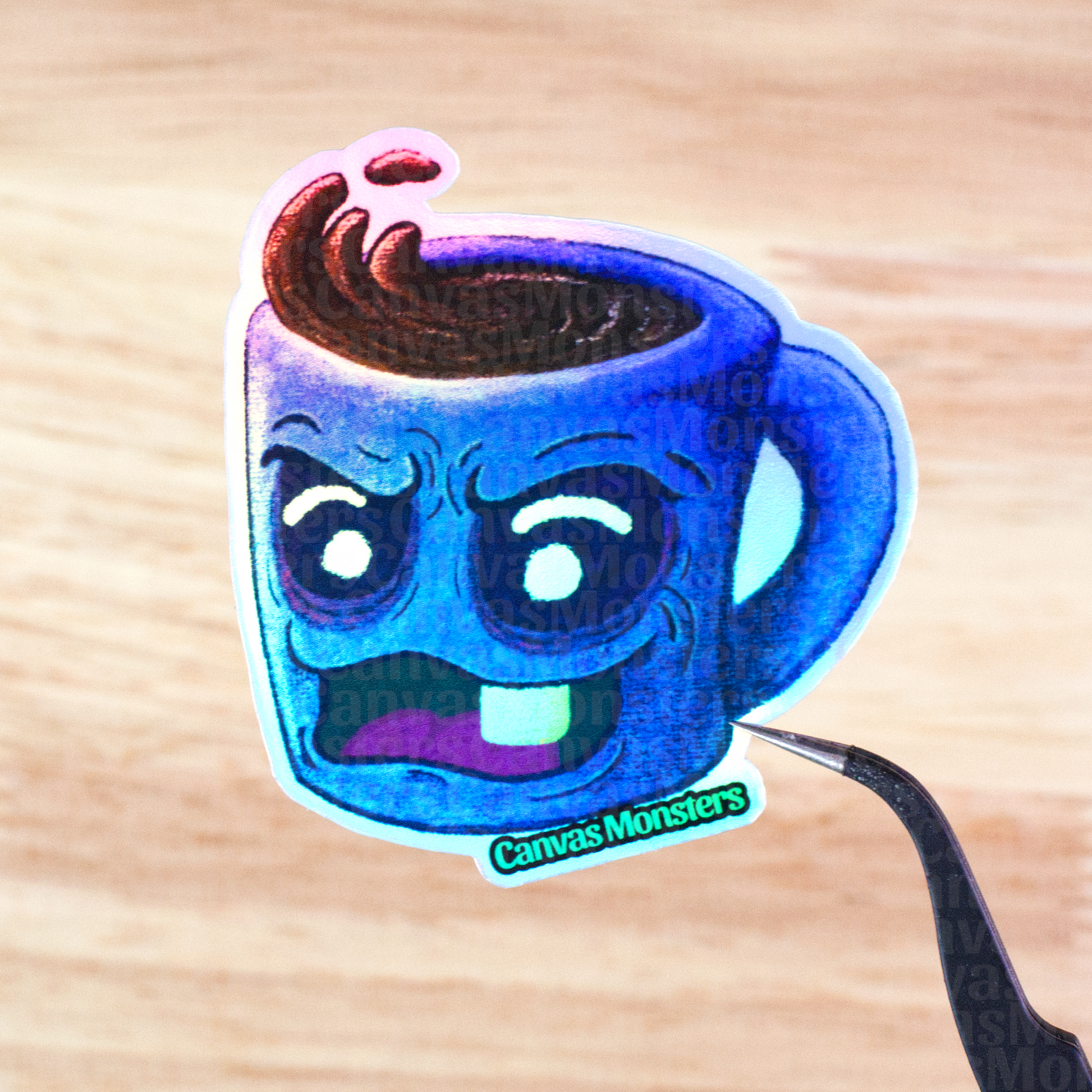 Holofoil sticker of a blue mug with an angry face held above a wooden surface, branded 'Canvas Monsters'.