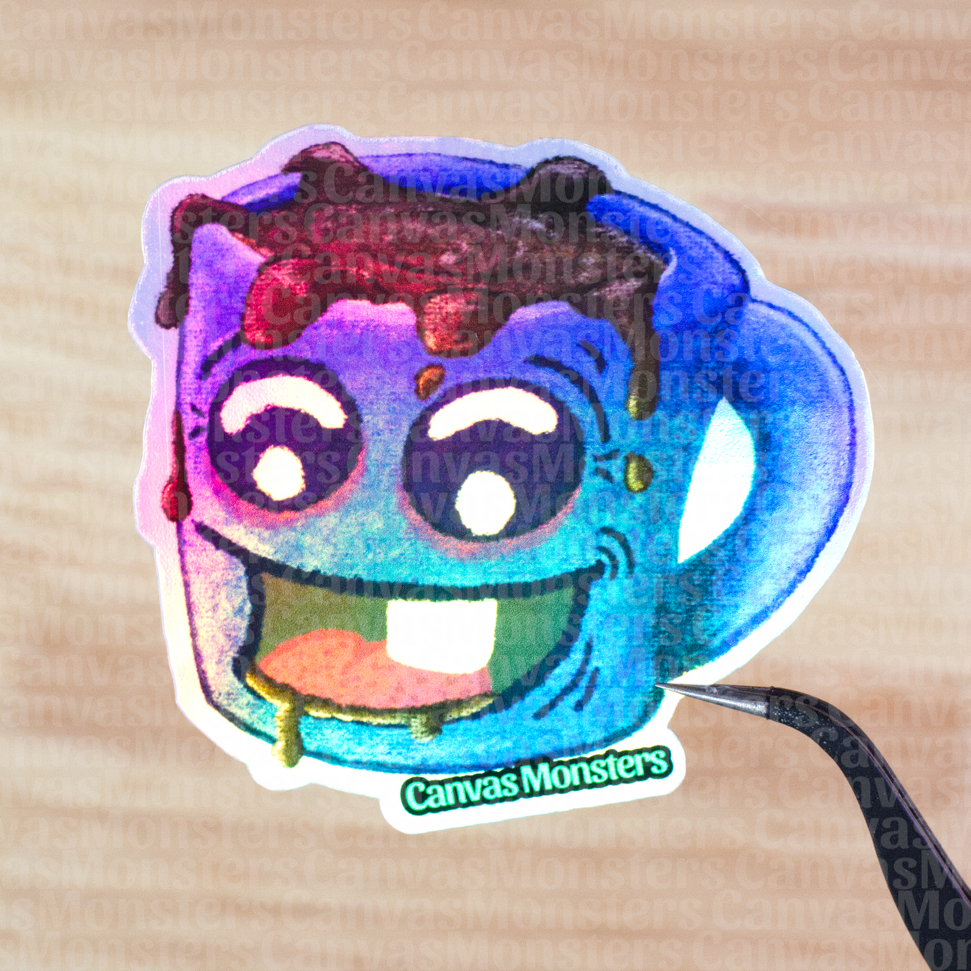 Holofoil sticker of a blue mug with a happy face and coffee spilling out held above a wooden surface, branded 'Canvas Monsters'.