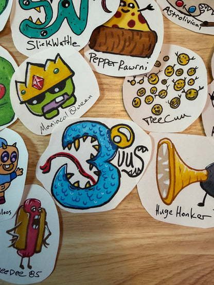 A collection of hand-drawn monster characters arranged on a light wood surface. Each monster has a username underneath it.