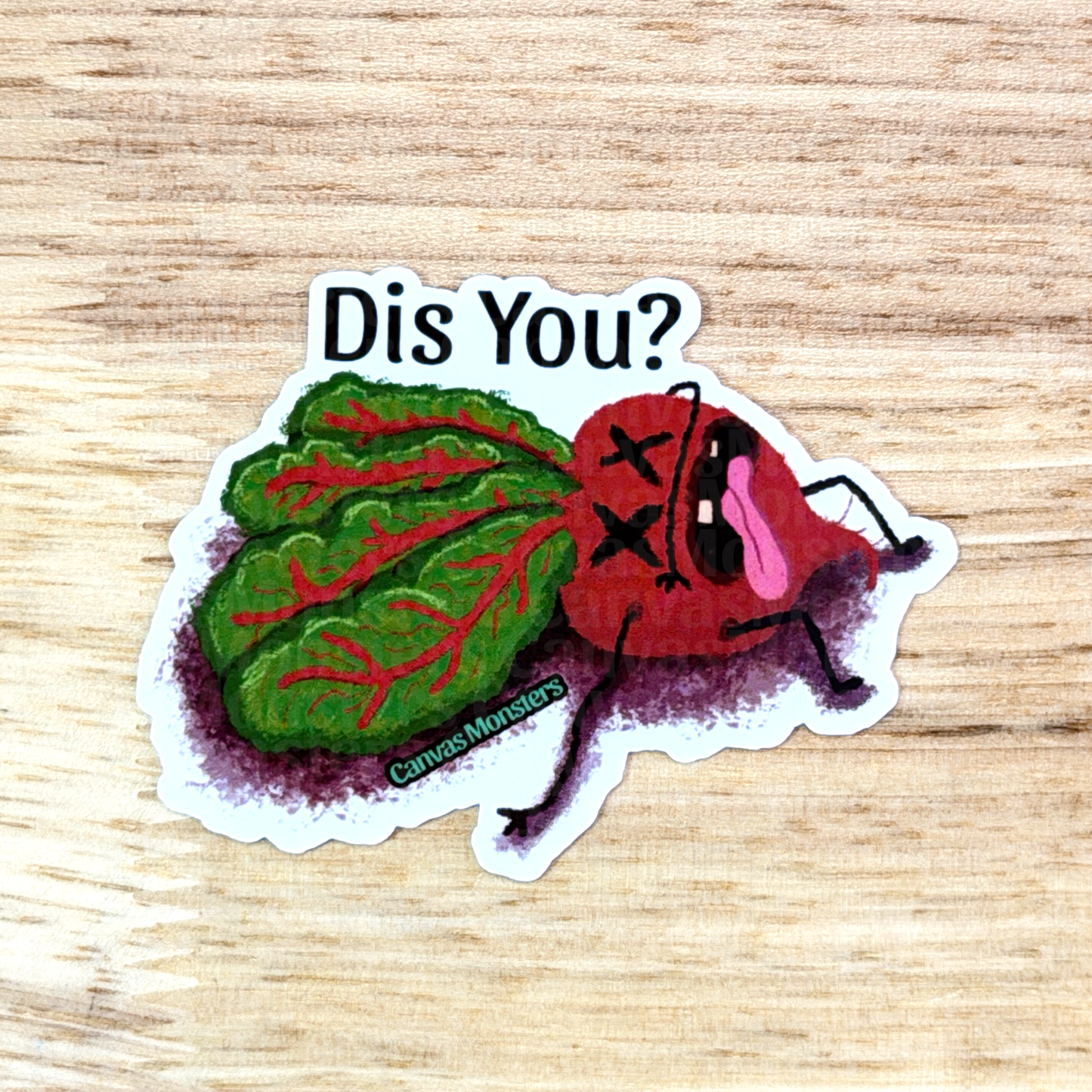 Sticker with a red and green characterized beet asking 'Dis You?' on a wooden surface