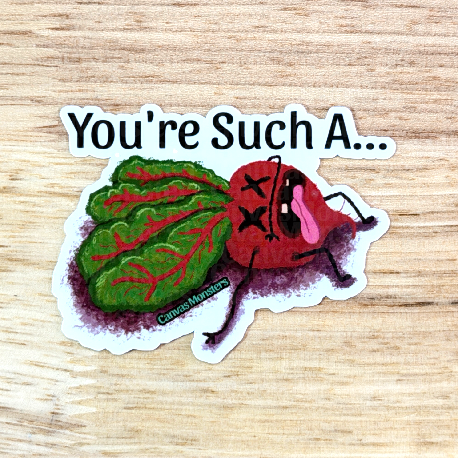 Cartoon characterized beet sticker with text 'You're Such A...' on a wooden surface