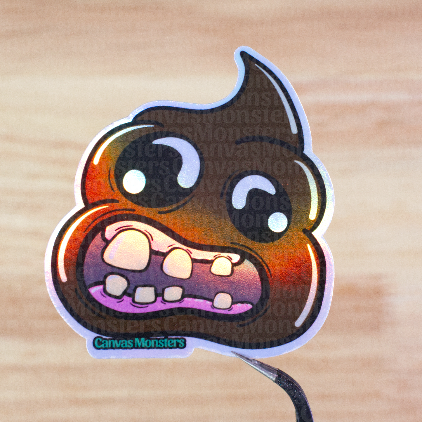 Holographic sticker of a cartoon poop emoji held above a wooden surface.
