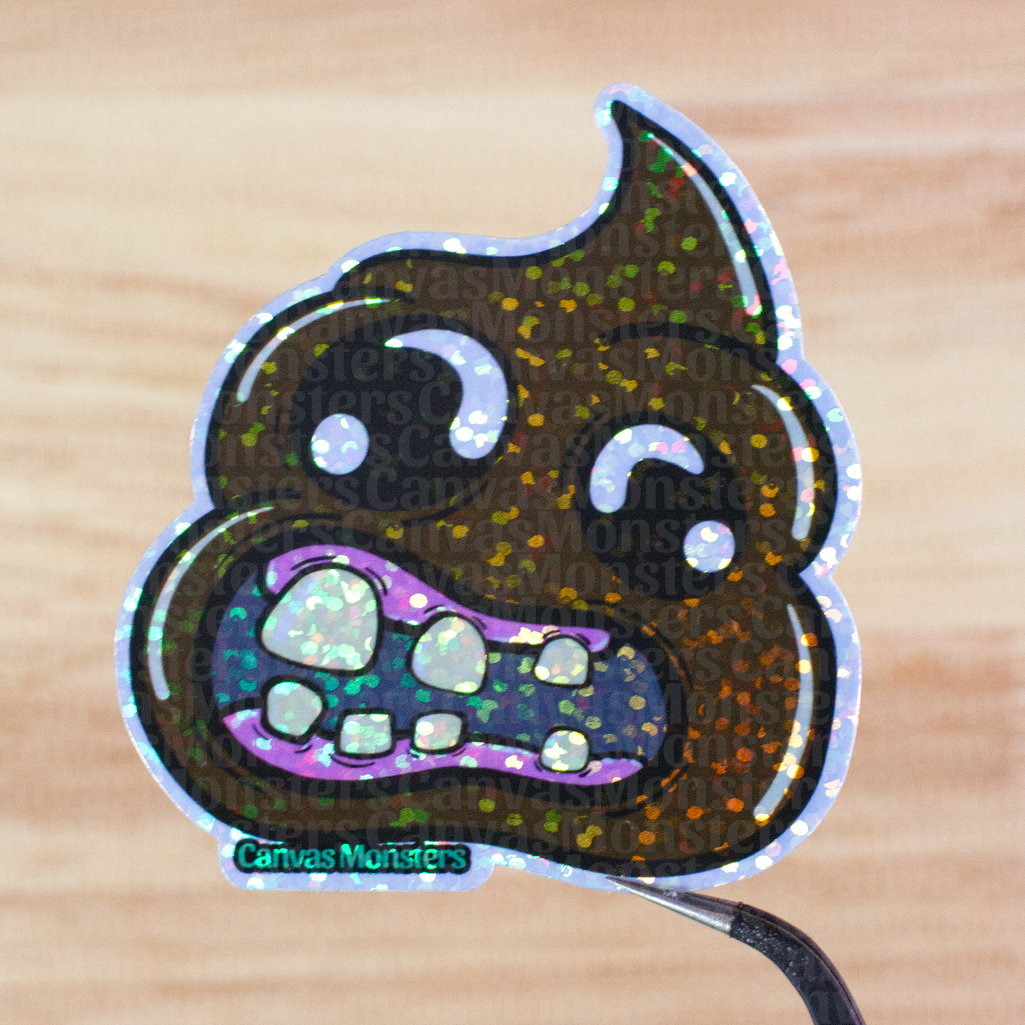 Glitter poop emoji sticker on a wooden surface