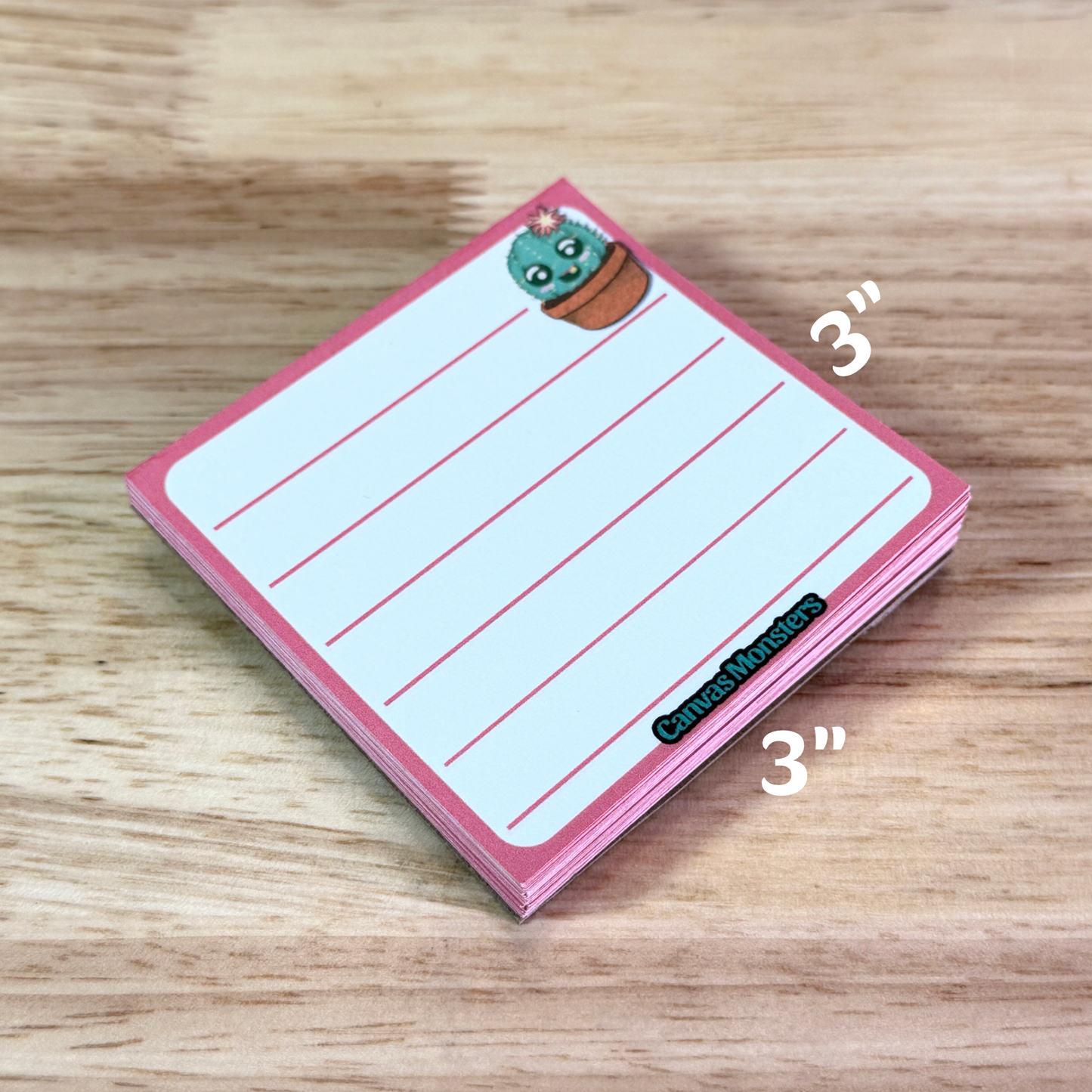 3x3 inch lined memo pad with a cartoon cactus character in the top right corner and 'Canvas Monsters' branding at the bottom, sitting on a wooden surface.