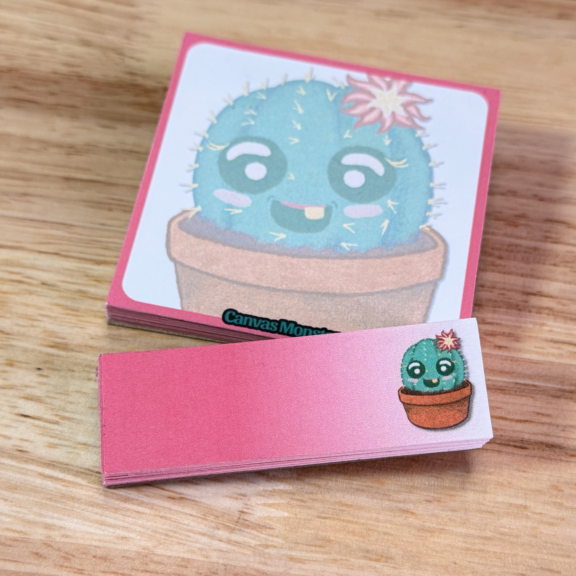 Sticky notepad set, one 3x3 and one 1x3, with a cartoon cactus illustration, sitting on a wooden surface