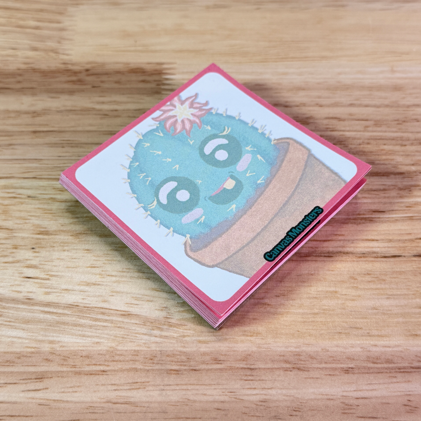 Sticky notepad with a cactus cartoon, sitting on a wooden surface