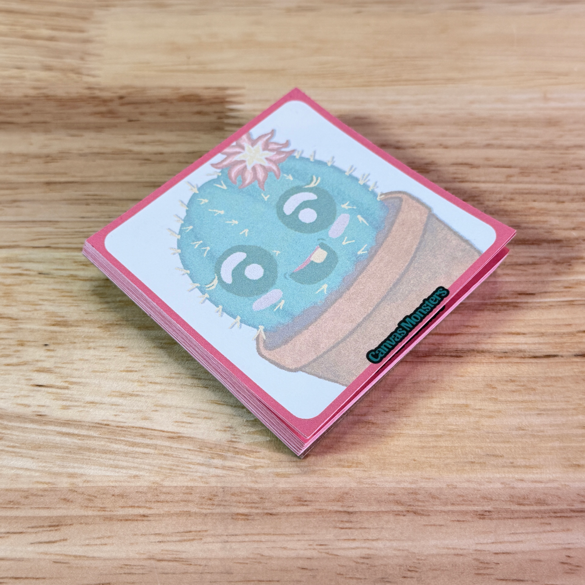 Sticky notepad with a cactus cartoon, sitting on a wooden surface