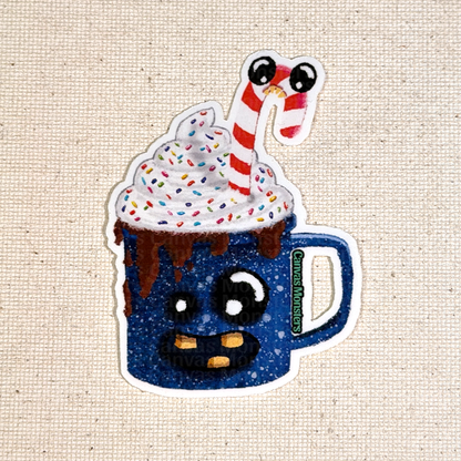 Glossy blue mug with whipped cream and candy cane held by a hand on a beige background