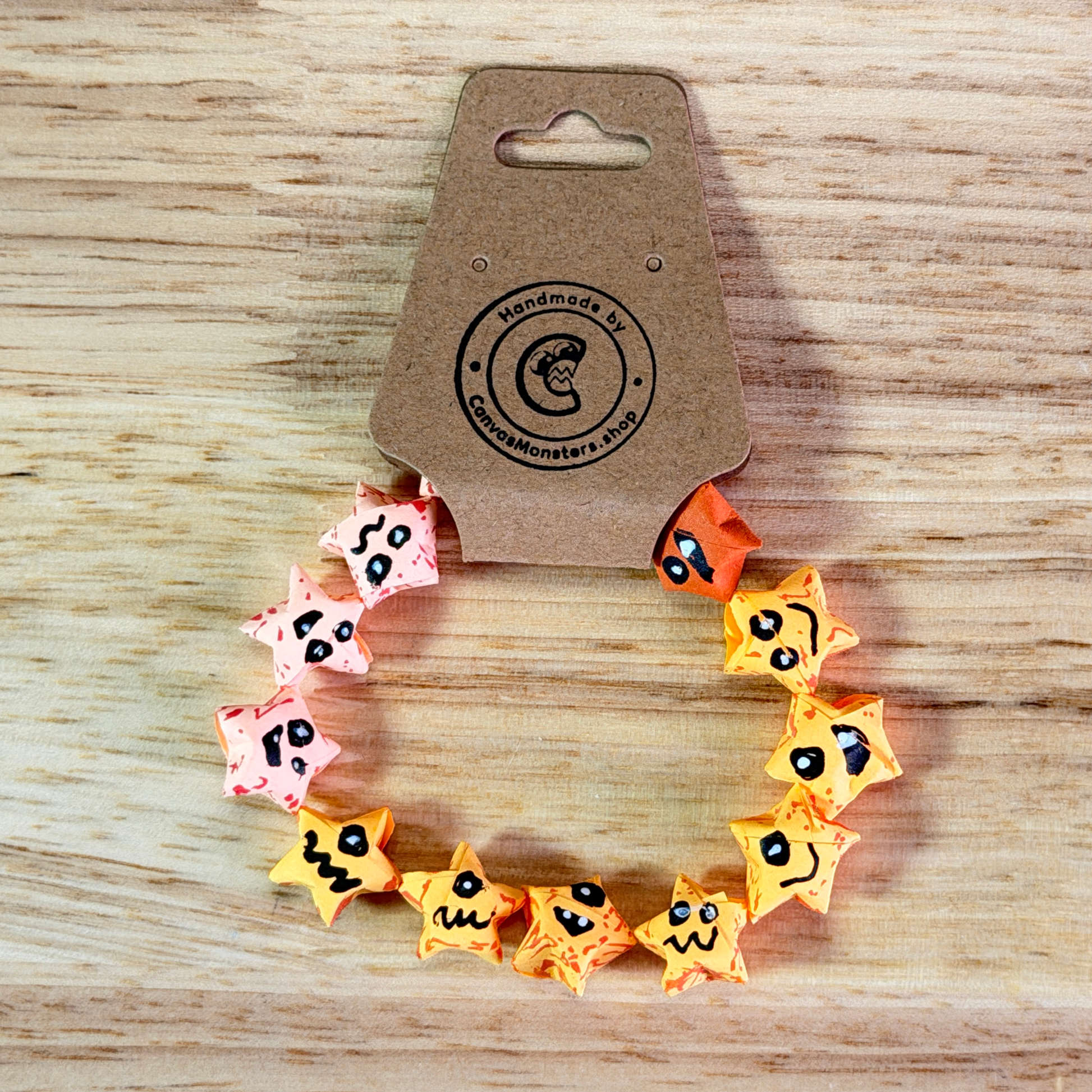 Bracelet with pink, yellow, and orange paper origami star-shaped charms on a beige background