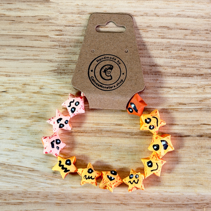 Bracelet with pink, yellow, and orange paper origami star-shaped charms on a beige background