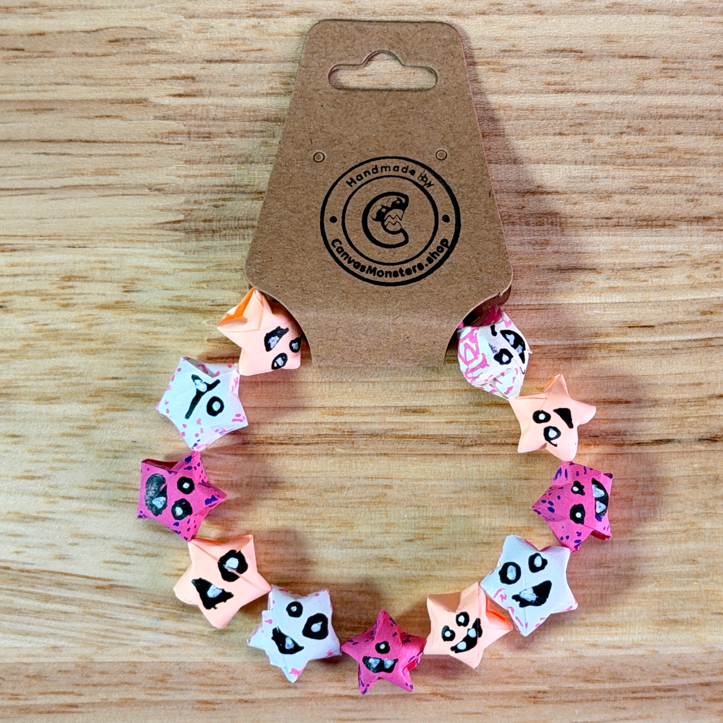 Bracelet with a gradiant of pink paper origami star-shaped charms on a beige background