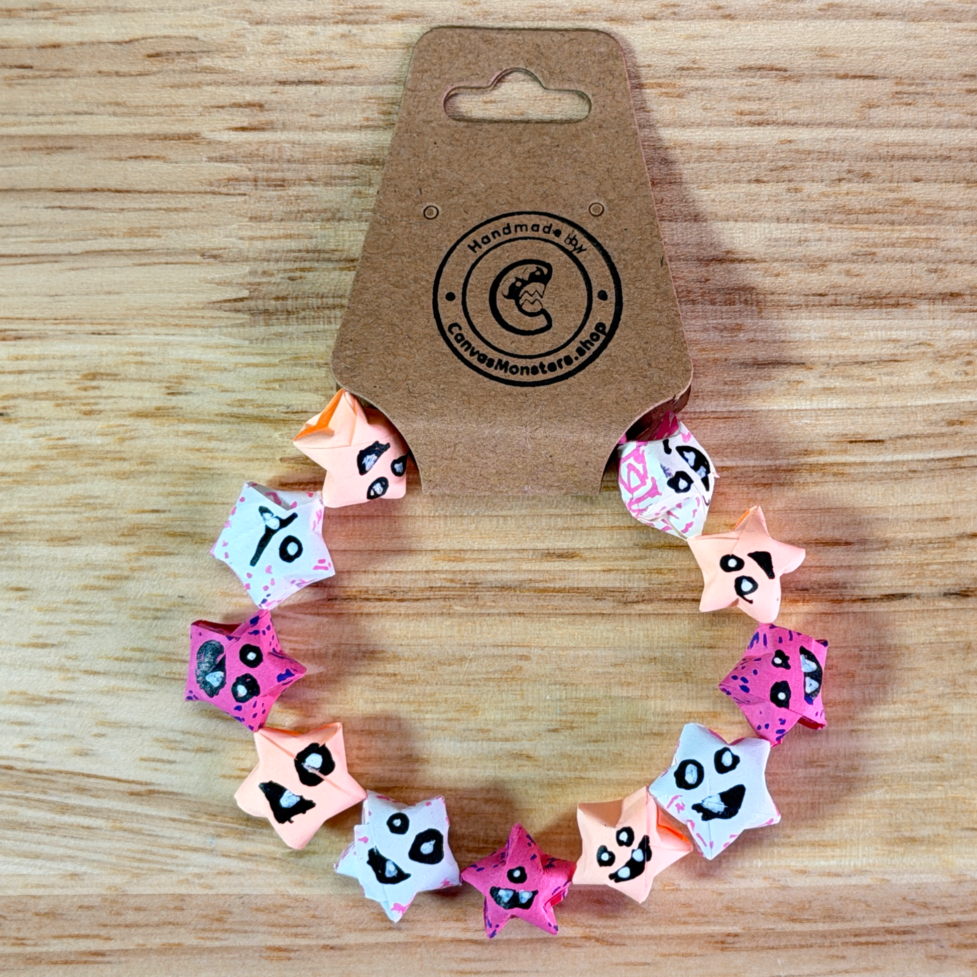 Bracelet with a gradiant of pink paper origami star-shaped charms on a beige background