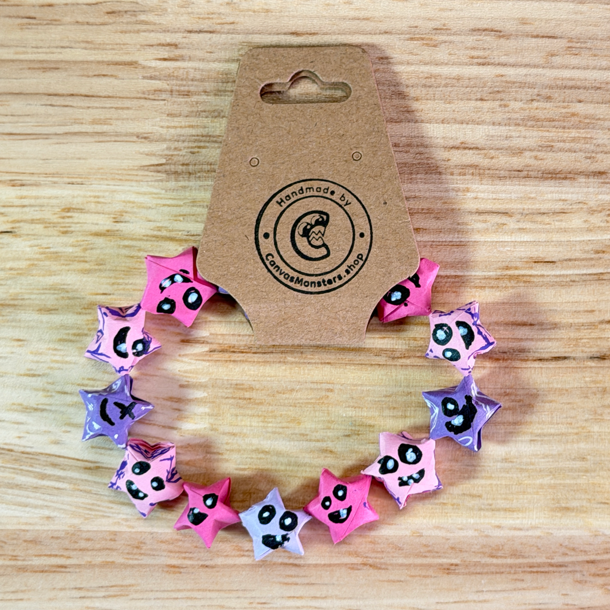Bracelet with pink and purple paper origami star-shaped charms on a wooden background