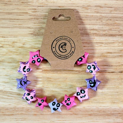 Bracelet with pink and purple paper origami star-shaped charms on a wooden background