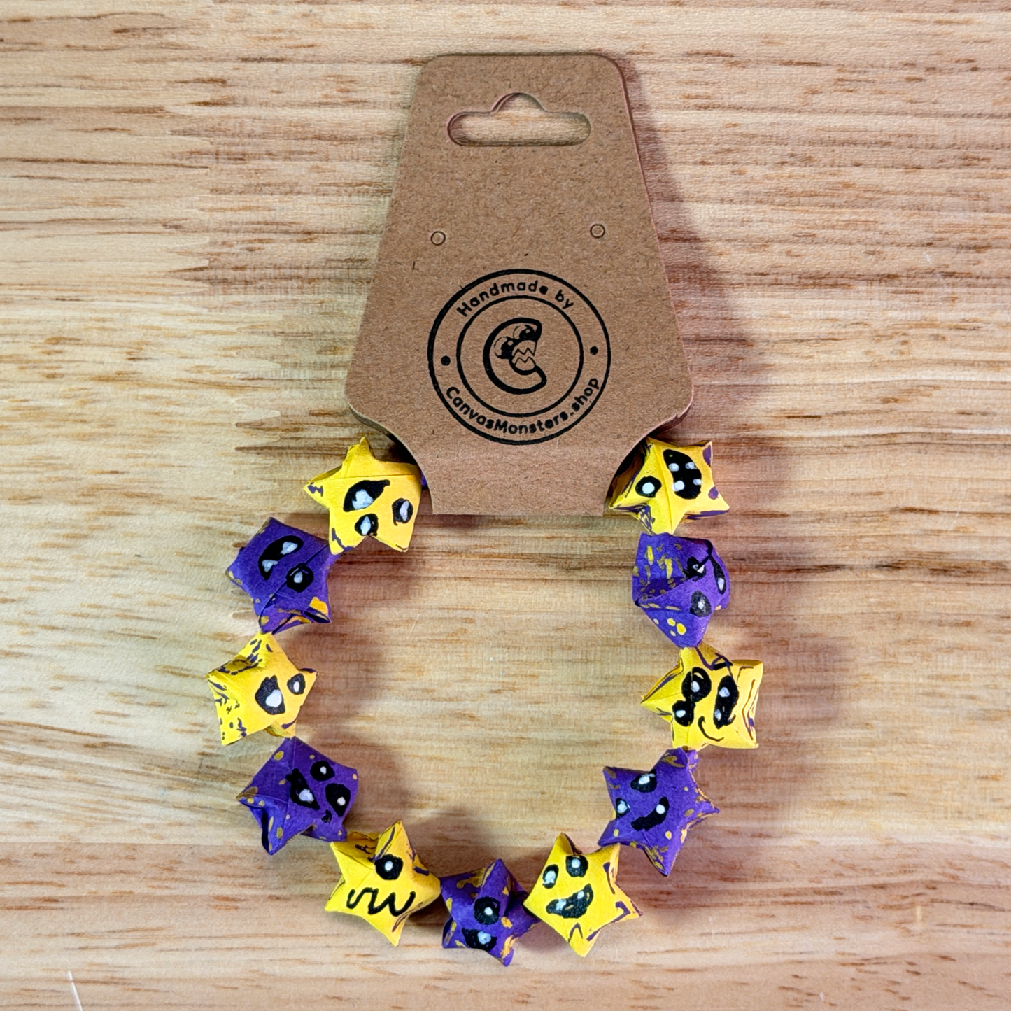 Bracelet with alternating purple and yellow paper origami star-shaped charms on a wooden background