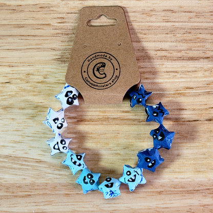 Bracelet with a gradiant of blue paper origami star-shaped charms on a wooden background
