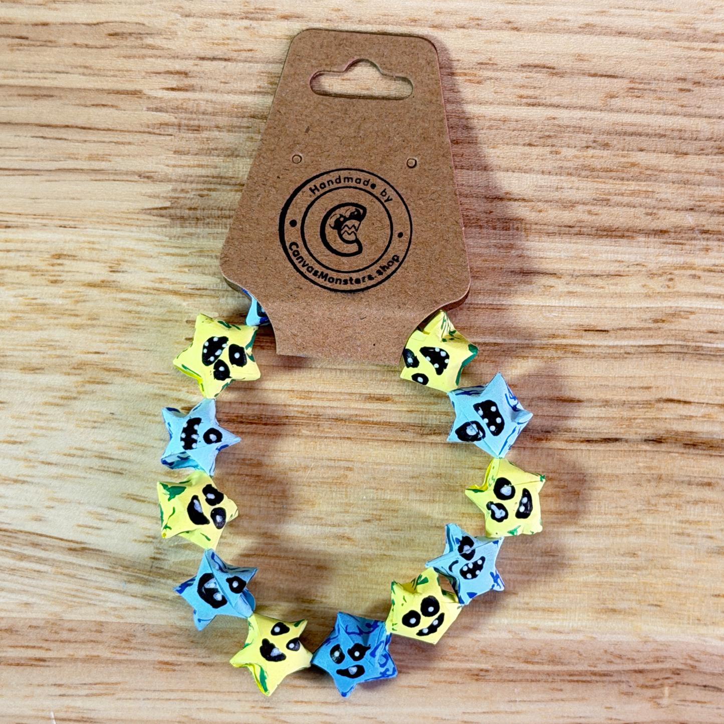 Bracelet with alternating blue and yellow paper origami star-shaped charms on a wooden background