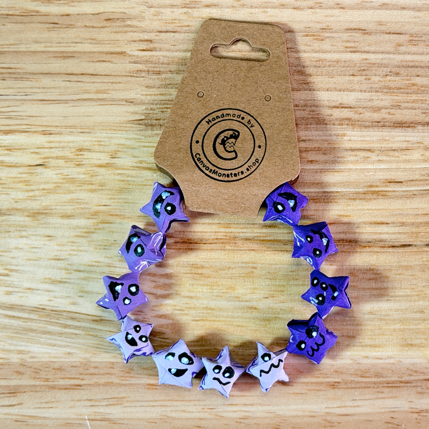 Bracelet with blue and purple paper origami star-shaped charms on a wooden background